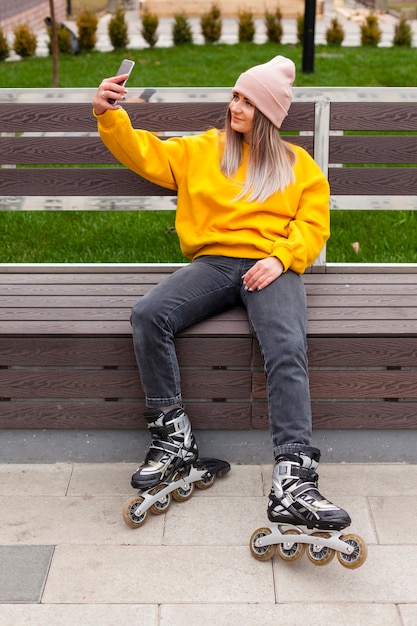 Mulher de patins tomando uma selfie no banco