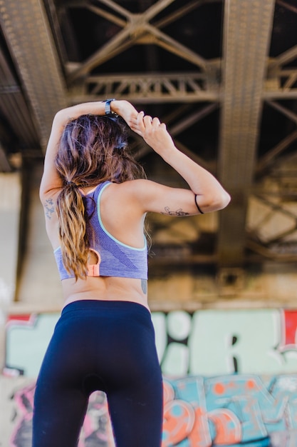 Foto grátis mulher de pé sob a ponte esticando os braços