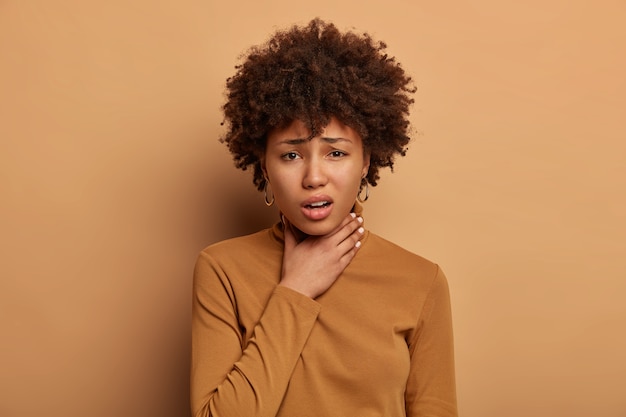 Foto grátis mulher de pele escura descontente com dor de garganta, dor após catarse gripe, enjoo e indisposição, rosto carrancudo