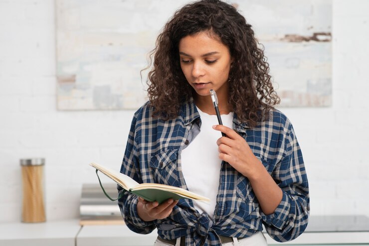 Foto grátis mulher de pensamento segurando um caderno e uma caneta