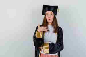 Foto grátis mulher de pós-graduação apontando para si mesma em roupas casuais, uniforme e parecendo surpresa. vista frontal.