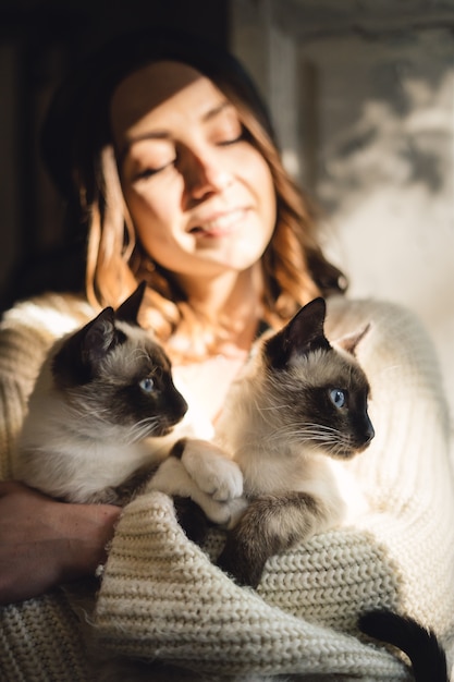 Mulher de retrato com gatos siameses