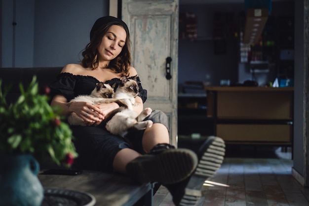 Mulher de retrato com gatos siameses