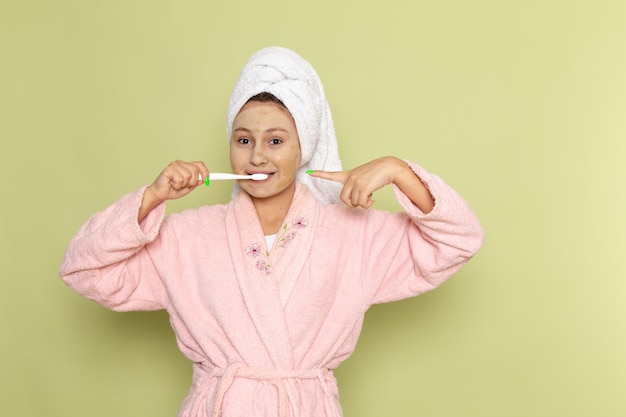 Mulher de roupão rosa limpando os dentes