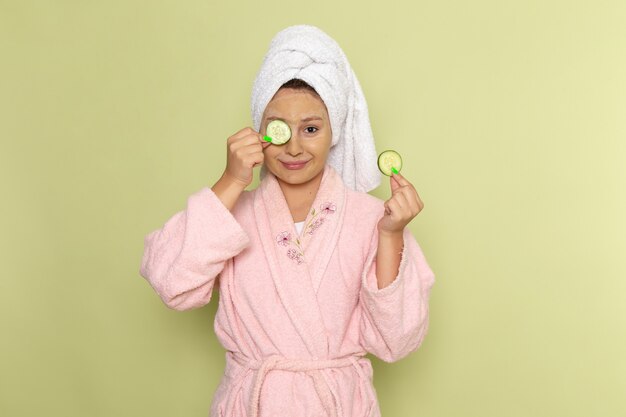 Mulher de roupão rosa segurando anéis de pepino