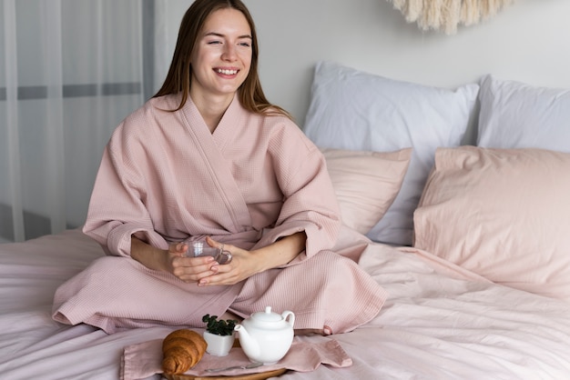 Foto grátis mulher de roupão tomando café da manhã na cama