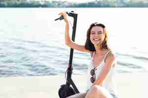 Foto grátis mulher de smiley vista frontal posando em scooter