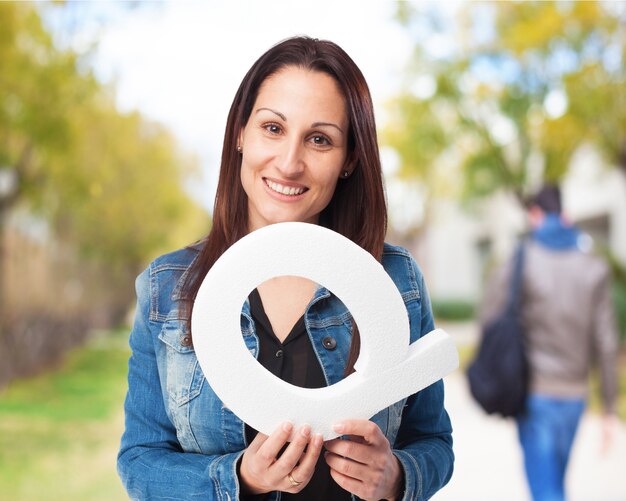 Mulher de sorriso que prende a letra &quot;q&quot;