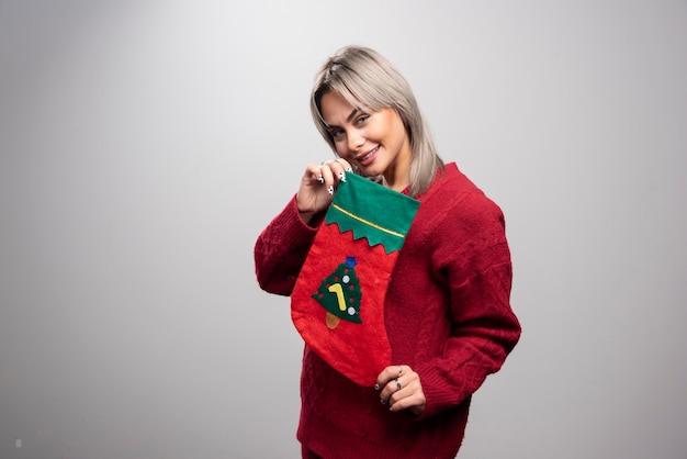 Foto grátis mulher de suéter vermelho, posando com meia de natal.