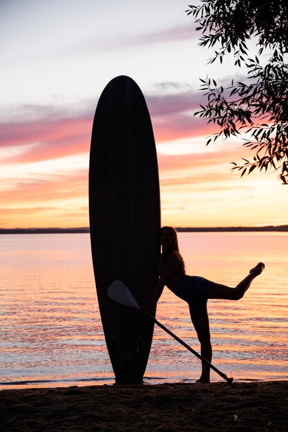 Mulher de tiro completo abraçando paddleboard