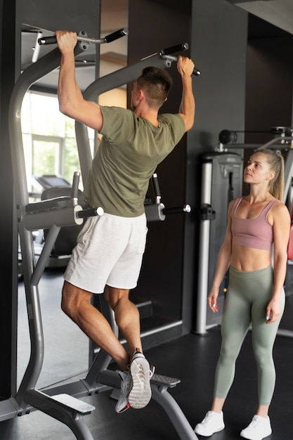 Foto grátis mulher de tiro completo ajudando o homem na academia