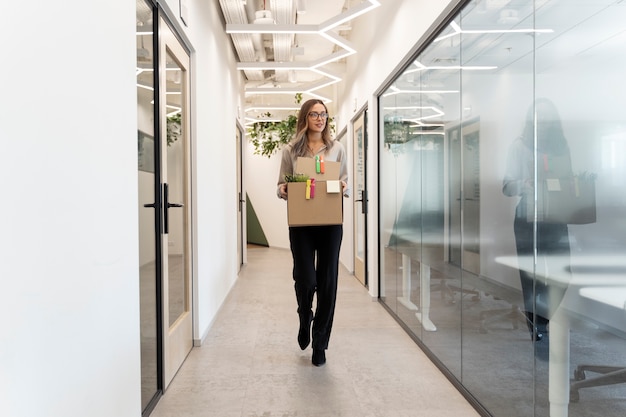 Mulher de tiro completo andando com caixa de papelão