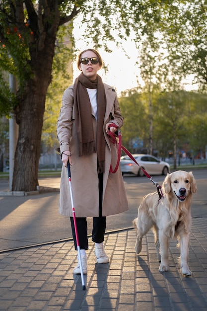 Mulher de tiro completo andando com cão de serviço