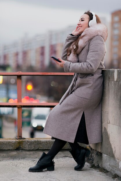 Mulher de tiro completo com fones de ouvido no telhado