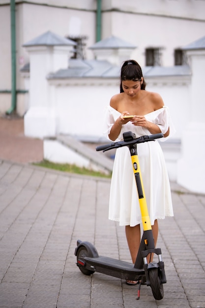 Foto grátis mulher de tiro completo com scooter ao ar livre