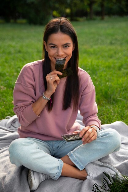 Mulher de tiro completo comendo lanche de algas