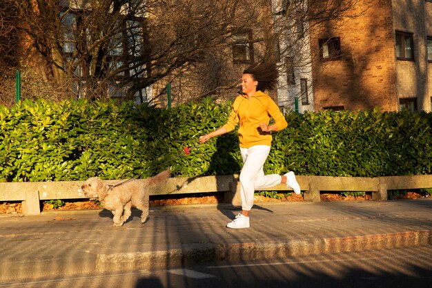 Mulher de tiro completo correndo com cachorro ao ar livre