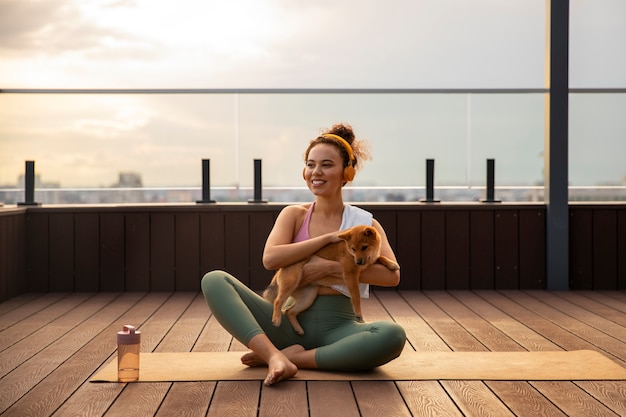 Mulher de tiro completo fazendo esporte acompanhada de cachorro