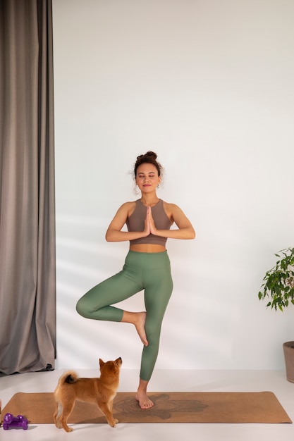 Foto grátis mulher de tiro completo fazendo esporte com cachorro dentro de casa