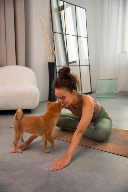 Mulher de tiro completo fazendo esporte com cachorro dentro de casa