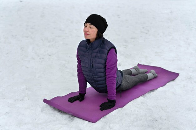 Mulher de tiro completo fazendo ioga em clima frio