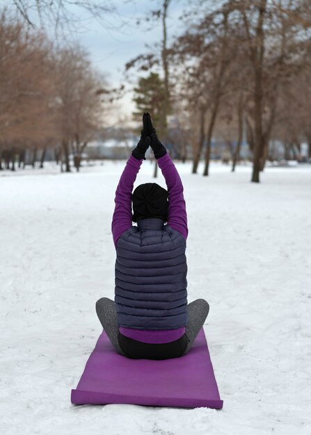 Mulher de tiro completo fazendo ioga em clima frio