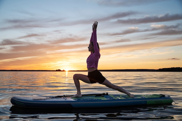 Mulher de tiro completo fazendo ioga no paddleboard