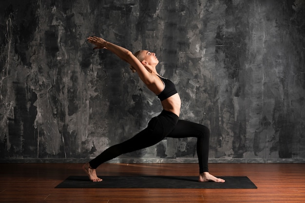 Mulher de tiro completo fazendo yoga na esteira