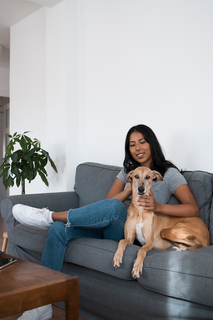 Mulher de tiro completo sentada no sofá com cachorro