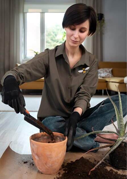 Mulher de tiro completo transplantando plantas em casa