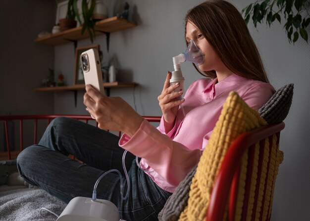 Mulher de tiro completo usando nebulizador em casa