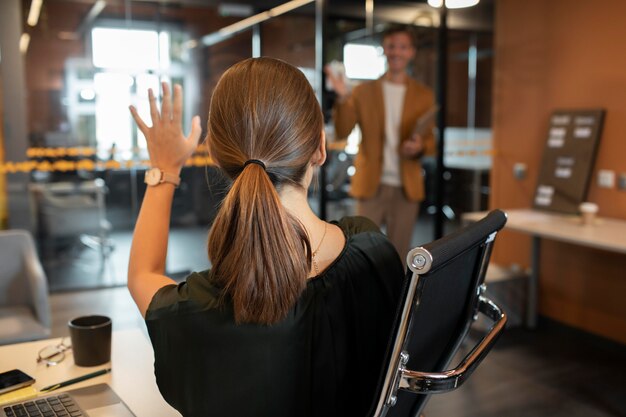 Mulher de tiro médio acenando com a mão para um colega