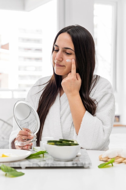 Mulher de tiro médio aplicando creme facial