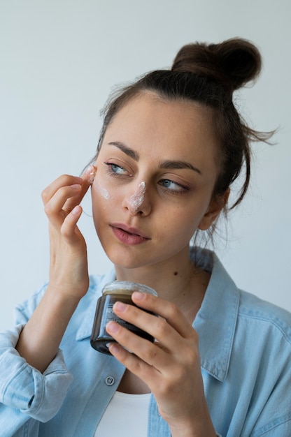 Mulher de tiro médio aplicando máscara facial