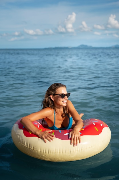 Foto grátis mulher de tiro médio com flutuador de donut