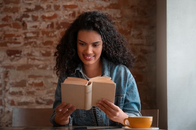 Foto grátis mulher de tiro médio com livro na cafeteria