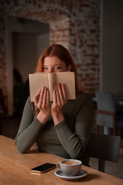 Mulher de tiro médio com livro na cafeteria