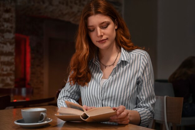 Mulher de tiro médio com livro na cafeteria