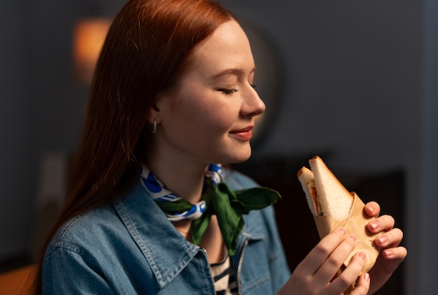 Mulher de tiro médio com sanduíche embrulhado em papel