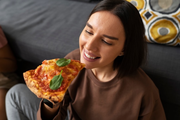 Mulher de tiro médio comendo pizza deliciosa