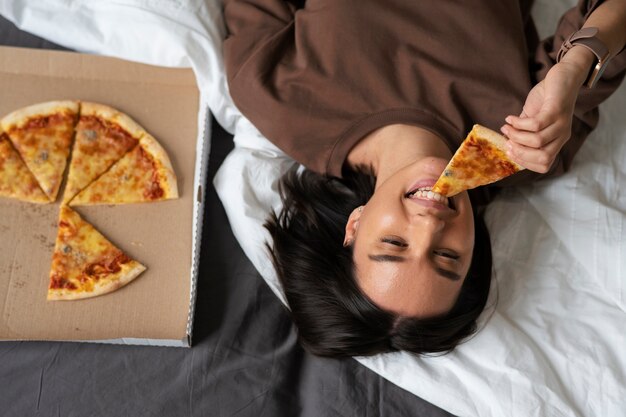Mulher de tiro médio comendo pizza deliciosa