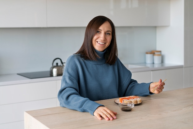 Mulher de tiro médio comendo sushi em casa