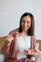 Foto grátis mulher de tiro médio comendo sushi em casa