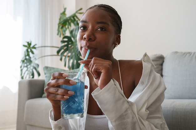 Mulher de tiro médio desfrutando de matcha azul em casa