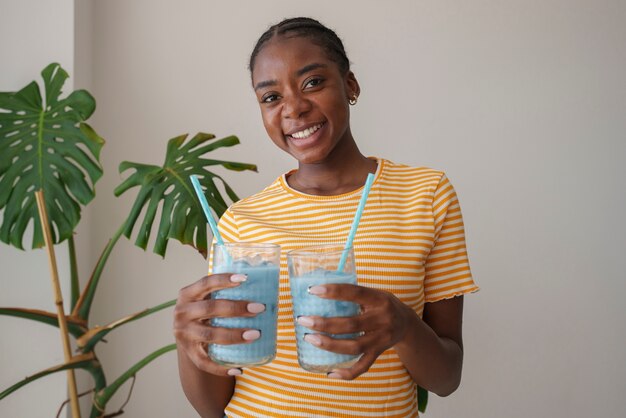 Mulher de tiro médio desfrutando de matcha azul em casa