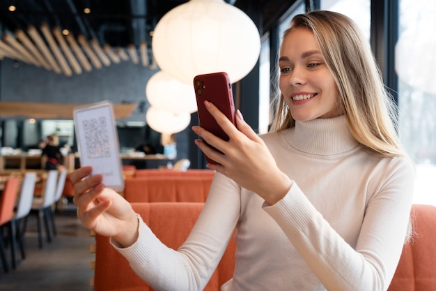 Mulher de tiro médio digitalizando qr com telefone