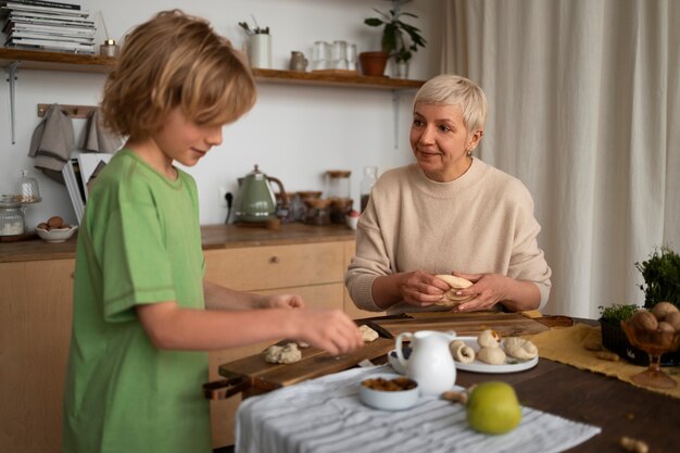 Mulher de tiro médio e criança preparando comida