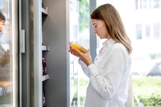 Foto grátis mulher de tiro médio lendo o rótulo do produto