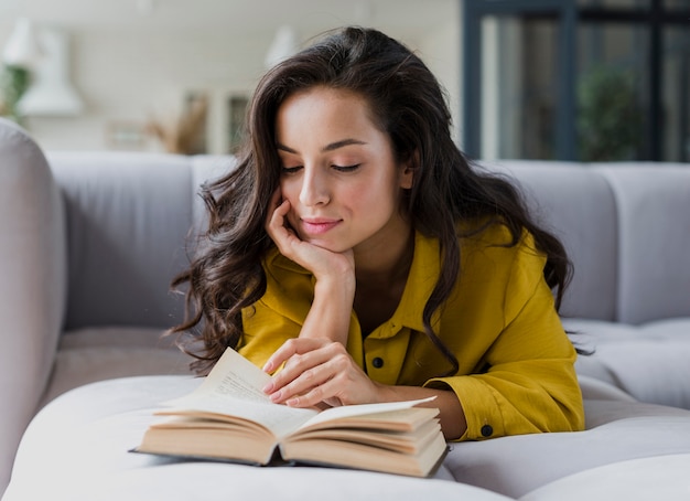 Foto grátis mulher de tiro médio na leitura do sofá