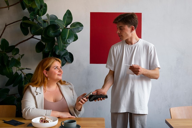Mulher de tiro médio pagando com dispositivo nfc
